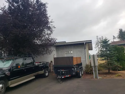 Ark Roofing & Renovations black work truck with dump trailer at job site in Tacoma, WA