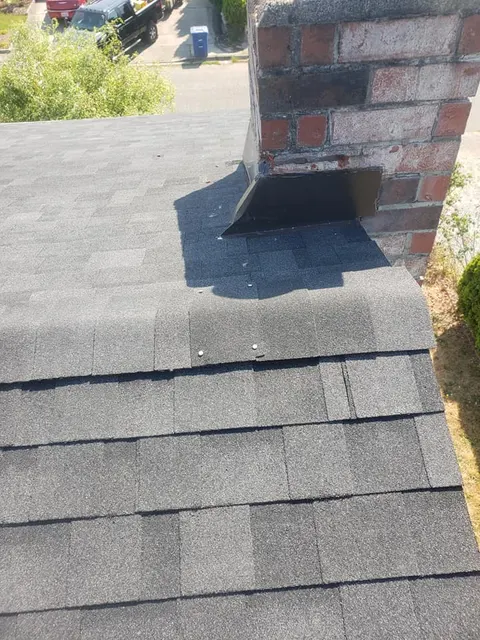 Brick chimney with damaged roof flashing requiring repair in Tacoma, WA
