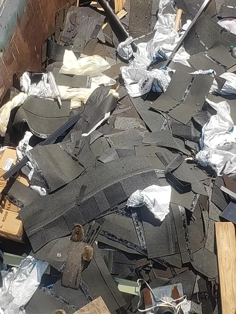 Dumpster full of old roofing tear-off debris from Tacoma roof replacement project